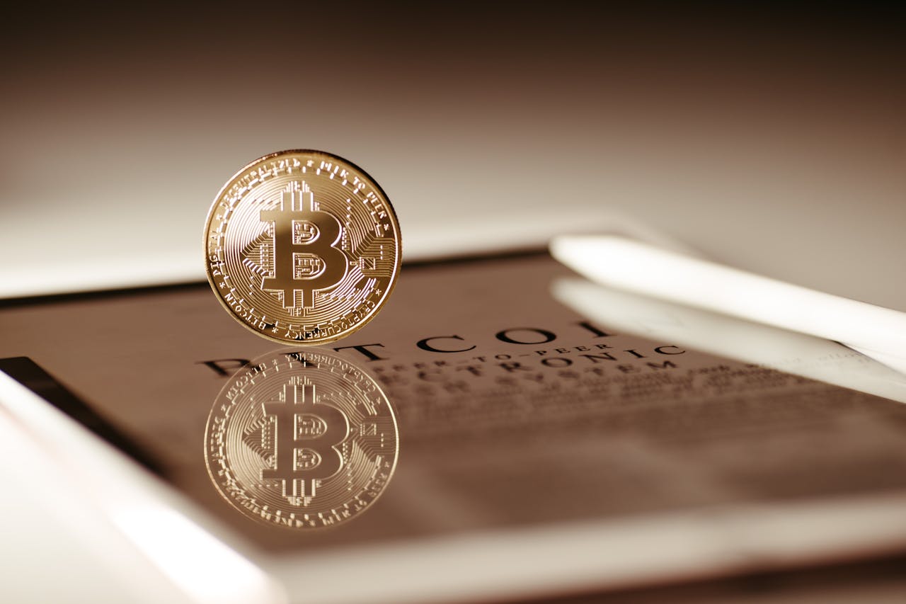 Close-up of a gold Bitcoin reflecting on a digital tablet screen, showcasing cryptocurrency concepts.