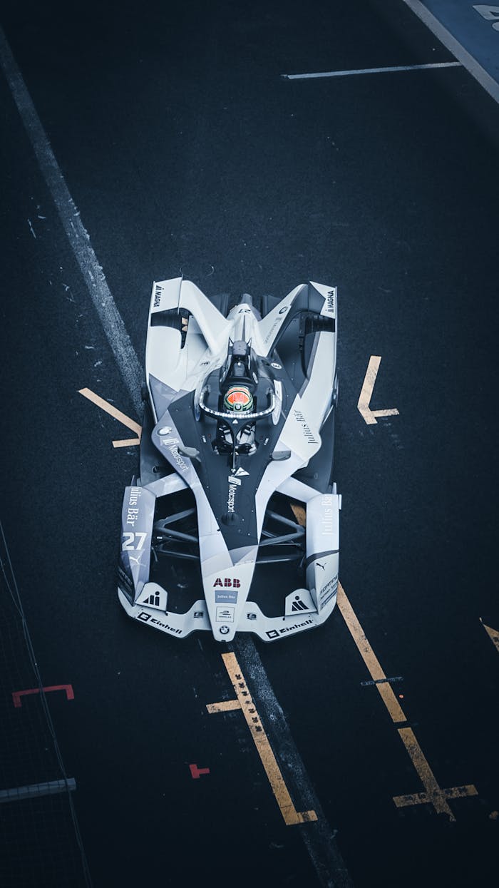 Top view of a dynamic Formula E car racing on a city street circuit, showcasing modern technology and speed.